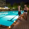 Due persone chiacchierano vicino a una piscina illuminata di sera.