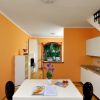 Cucina arancione con tavolo bianco e scala laterale.