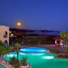 Piscina illuminata al tramonto, vista mare.