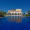 Edificio coloniale con piscina e ombrelloni blu.