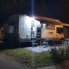 Camper illuminato di notte con tavolo fuori.