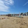 Persone sulla spiaggia con ombrelloni verdi.