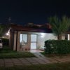 Casa piccola illuminata di notte con auto parcheggiata accanto.