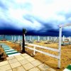 Spiaggia con ombrelloni sotto cielo nuvoloso.
