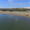 Spiaggia tranquilla con ombrelloni e colline.