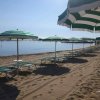 Spiaggia con ombrelloni e lettini verdi fronte mare.
