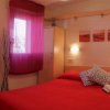 Camera da letto con letto rosso, cuscini decorativi e televisore.