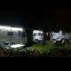 Campeggio notturno con roulotte illuminate.