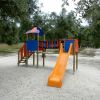 Scivolo arancione nell'area giochi tra gli alberi.