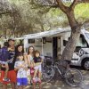 Famiglia davanti a un camper tra gli alberi.