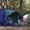 Una tenda blu con telo verde e sedie da campeggio.
