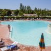 Piscina con sdraio e ombrelloni, circondata da palme.