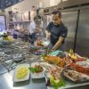 Chef cucina pesce fresco in una cucina industriale.