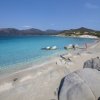 Spiaggia sabbiosa con rocce e mare turchese.