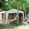 Un'area campeggio con una tenda grande, circondata da alberi e sedie a sdraio.