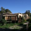 Casa con tetto in tegole tra alberi e piante verdi.