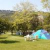 Tenda da campeggio in un prato verde circondato da alberi e colline.