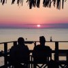 Due persone guardano un tramonto sul mare.