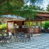 Bar all'aperto con tavoli e ombrellone su pavimento a scacchi.