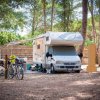 Camper parcheggiato tra gli alberi con biciclette affiancate.