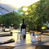 Tavolo apparecchiato all'aperto con bottiglie di vino e bicchieri.