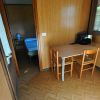 Interno di una stanza con tavolo, due sedie, scaffale e letto in una camera adiacente.