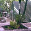Un prefabbricato verde tra alberi e vialetti in pietra.