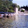 Spiaggia con ombrelloni blu, persone in acqua e edifici sullo sfondo.