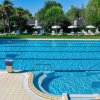 Piscina con getto d'acqua e ombrelloni.