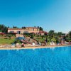 Piscina grande con sdraio e vegetazione circostante.