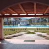 Vista di una piscina incorniciata tra due colonne sotto un portico di legno.