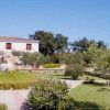 Giardino curato con alberi e un edificio bianco a due piani sullo sfondo.