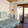 Una camera da letto con letto matrimoniale, copriletto a quadri e una terrazza soleggiata con sedie.