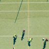 Partita di calcio vista dall'alto su campo verde.