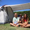 Tre ragazzi seduti davanti a una tenda da campeggio.