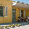 Casa gialla con persone sedute a un tavolo esterno.