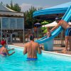 Bambini che giocano in piscina con scivolo.