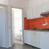 Cucina con piastrelle arancioni e mobili bianchi.