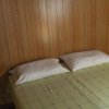 Letto matrimoniale con cuscini bianchi su parete in legno.