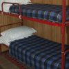 Letto a castello con struttura rossa e coperte a quadri blu e neri.