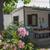 Bungalow bianco con veranda e fiori rosa intorno.