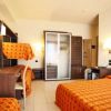 Camera d'hotel con letto matrimoniale, letto a castello, scrivania, TV e armadio bianco.