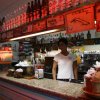 Bar con bottiglie di alcolici e una persona dietro il bancone.