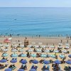 Spiaggia affollata con ombrelloni e lettini blu.