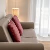 Divano beige con cuscini rossi e lampada accesa.