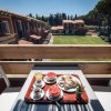 Colazione su terrazza con vista su giardino e palazzi.