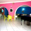 Interno colorato con pareti rosa e blu, tavolini gialli e un pianoforte nero.
