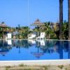 Piscina riflettente con palme e sedie a sdraio bianche.