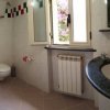 Bagno bianco con doccia, lavandino e finestra.
