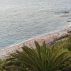 Vista dall'alto di una spiaggia con ombrelloni arancioni e palme.